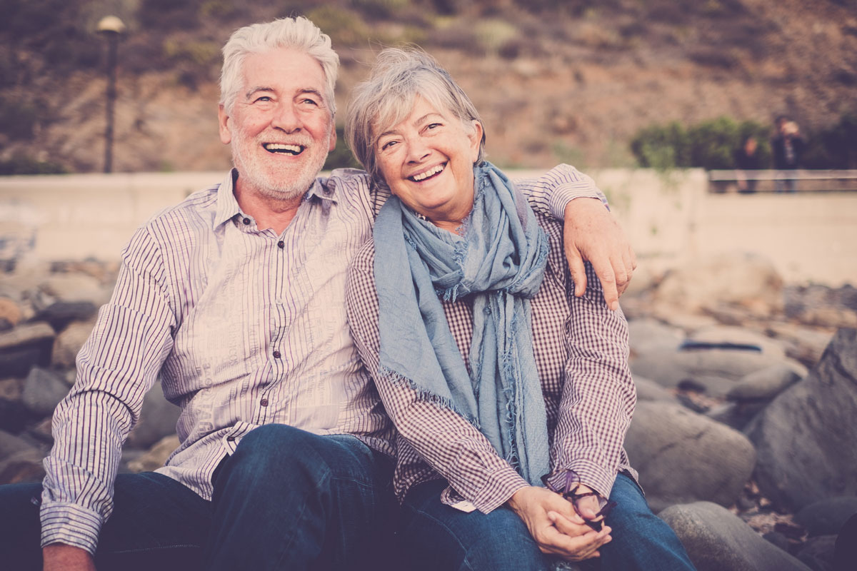 happy-elder-couple-sitting-at-park-bench